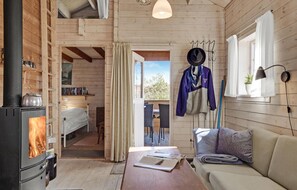 Cozy cabin-style room with a central fireplace, comfortable sofa, and dining table.