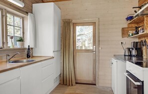Compact kitchen with oven, coffee maker, and stainless steel sink.