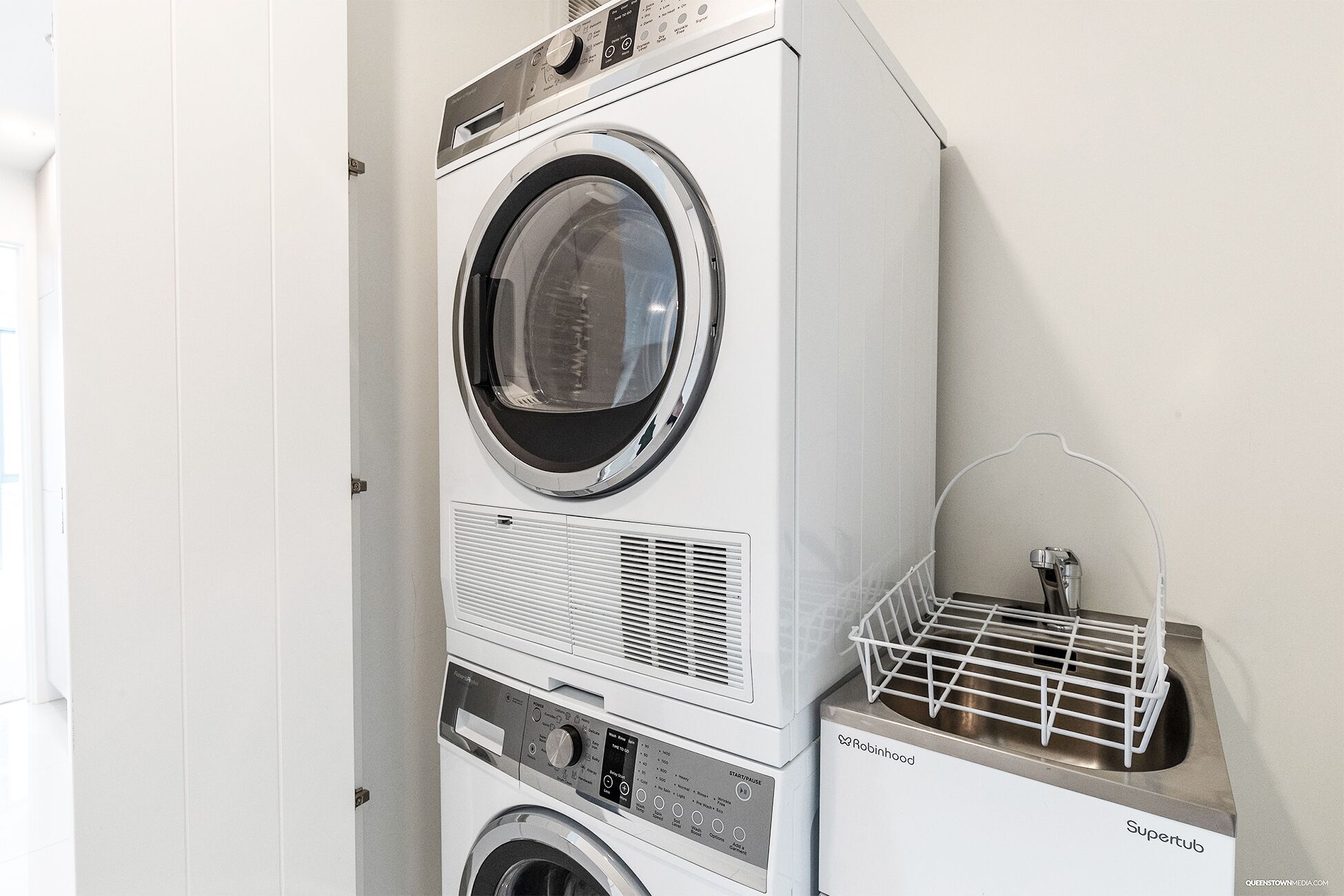 A stacked washer and dryer unit with a small dish rack on top.