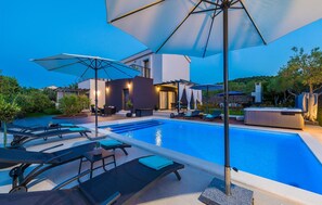 A modern outdoor pool area with lounge chairs, umbrellas, and a hot tub. - Amazing home in Zdrelac (Zdrelac)
