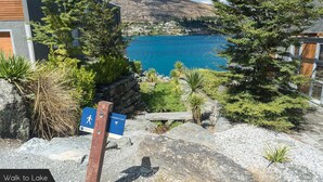 A path leading to a lake with a sign indicating a walking route. - Alpine Village - 2 Bedroom Executive Apartment (Queenstown)