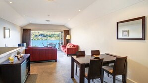 A hotel room with a balcony, a dining area, and a living space. - Alpine Village - 2 Bedroom Executive Apartment (Queenstown)