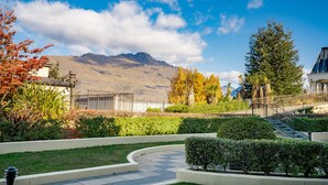 Un patio ajardinado con un sendero, una escalera y montañas al fondo.