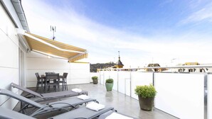 A rooftop terrace with sun loungers, a table, chairs, and potted plants. - Atlantic | Rentals Collection (San Sebastián)