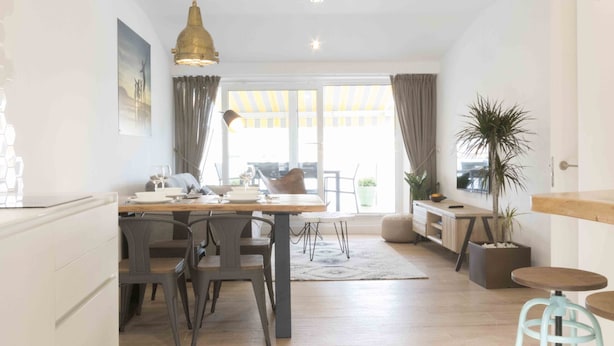 A modern kitchen with a dining area, a large window with curtains, and a view of the outdoors. - Atlantic | Rentals Collection (San Sebastián)
