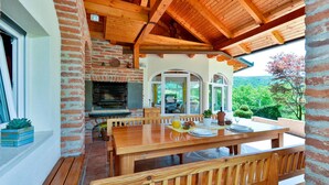 A wooden dining area with a brick fireplace, a table set for two, and a view of the outdoors. - Nice home in Varazdin Breg with sauna (Varazdin Breg)
