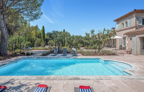 A swimming pool with lounge chairs, surrounded by trees and a building with a tiled roof. - Stunning home in Saint-Rémy-de-Provence (Saint-Rémy-de-Provence)