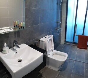 A modern bathroom with a white sink, a toilet, and a glass shower enclosure. - Almas Suites By Iconic Bliss (Iskandar Puteri)