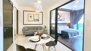 Moderni hotellihuone, jossa on sohva, ruokapöytä ja suuri sänky.