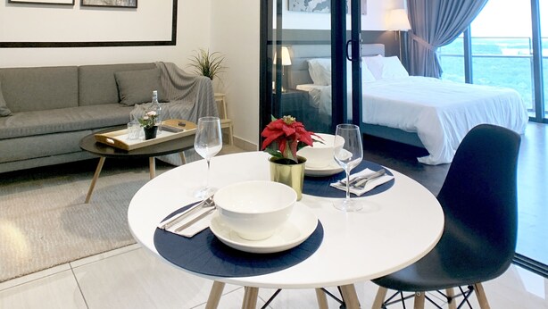 Moderni hotellihuone, jossa on ruokailutila, sohva, näköalalla varustettu sänky ja suuri ikkuna.