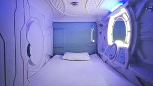 Ein Zimmer mit einem Bett, einer Bedienkonsole und einem Rundfenster.