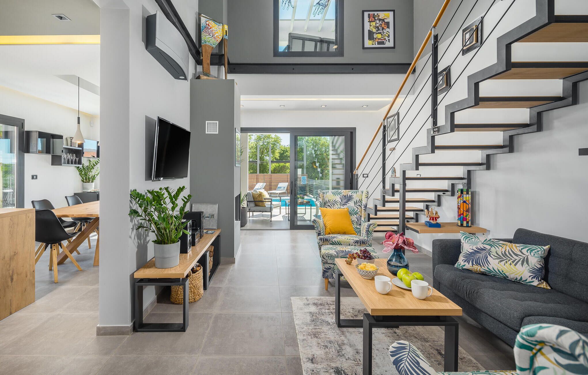Un salon moderne avec un escalier, un coin repas et une vue sur l’extérieur.