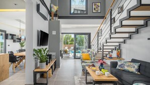 Een moderne woonkamer met een trap, een eethoek en uitzicht op de omgeving.