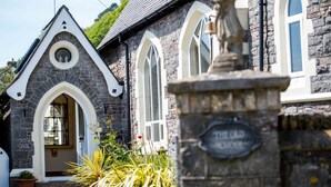 A stone building with arched windows and a bell tower. - Unique historic school‑house conversion with log burner (Laugharne (2.8miles W))