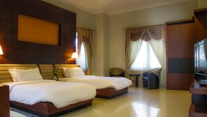 Une chambre d’hôtel avec deux lits, un bureau, une chaise et un téléviseur.