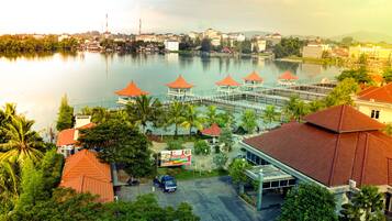 A lakeside hotel with multiple red-roofed structures, a parking area, and surrounding greenery.