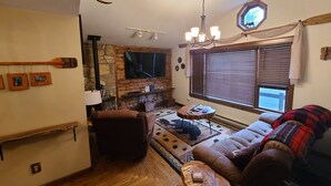 Una sala de estar acogedora con chimenea de piedra, un televisor grande y un sofá cómodo.