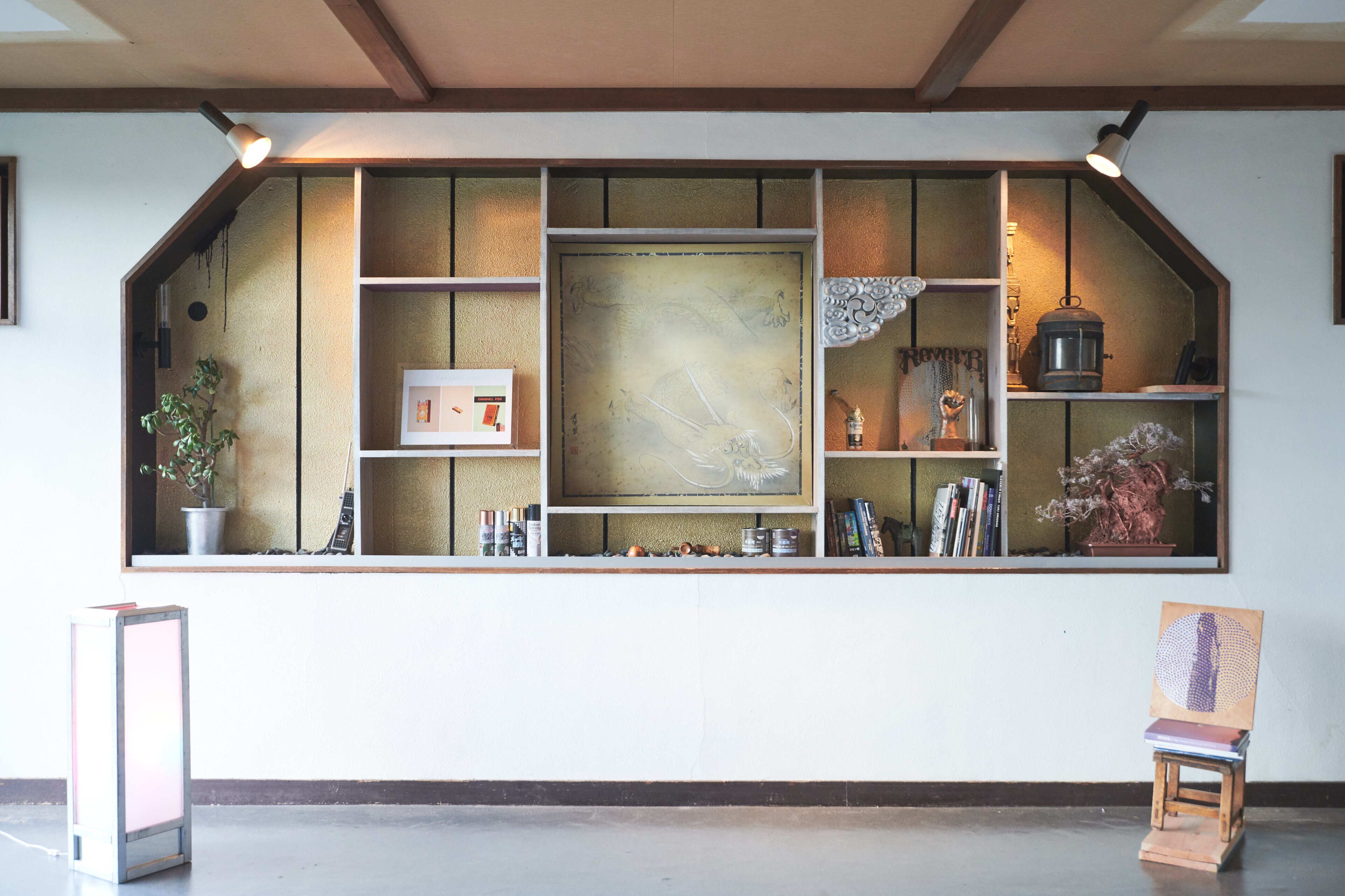 A reception area with a large window, shelves with various items, and a small easel with a painting.