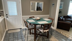 Un comedor con una mesa redonda, cuatro sillas y una alfombra.