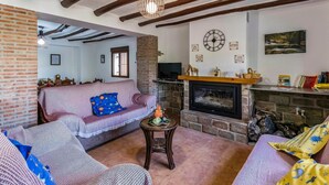 Een gezellige woonkamer met een open haard, een televisie en een bakstenen muur.