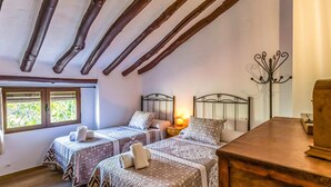 Een knus slaapkamer met twee bedden, houten balken, een nachtkastje met lamp en een dressoir.
