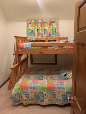 A bunk bed with a colorful quilt and a wooden ladder.