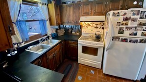 A kitchen with wooden cabinets, a stove, a sink, and a refrigerator. - Woody Creek On-Mountain Ski House - 6 Bedroom, Sleeps 10, Pool Table (Carrabassett Valley)