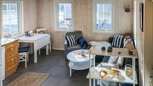 Een gezellige kamer met houten inrichting, een wit bureau, een grijze bank en een klein rond tafeltje met decoratieve objecten.