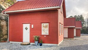 Een rode houten woning met een pannendak, een witte deur en twee ramen.
