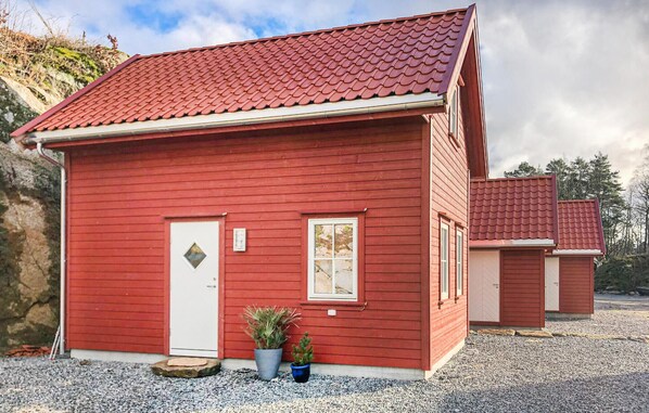 A red wooden house with a tiled roof, a white door, and two windows. - Lovely home in Lyngdal with WiFi (Lyngdal)