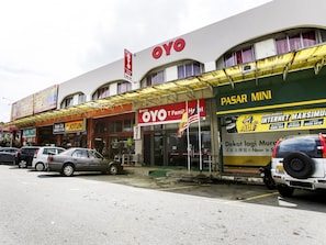 A hotel with a prominent 'OYO' sign, a 'Pasar Mini' shop, and several parked cars. - OYO 89615 T Family Hotel (Klang)
