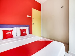A hotel room with a bed, two red pillows with "OYO" logo, a yellow door, and a white wall. - OYO 89615 T Family Hotel (Klang)