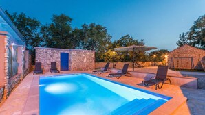 A swimming pool with lounge chairs, a stone wall, and a door. - Beautiful home in Sukosan (Sukosan)