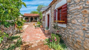 A stone building with red shutters, a brick pathway, and potted plants. - Beautiful home in Sukosan (Sukosan)