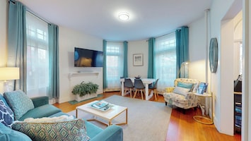 Chic living room with smart TV, dining area, and natural light, single chair, sofa