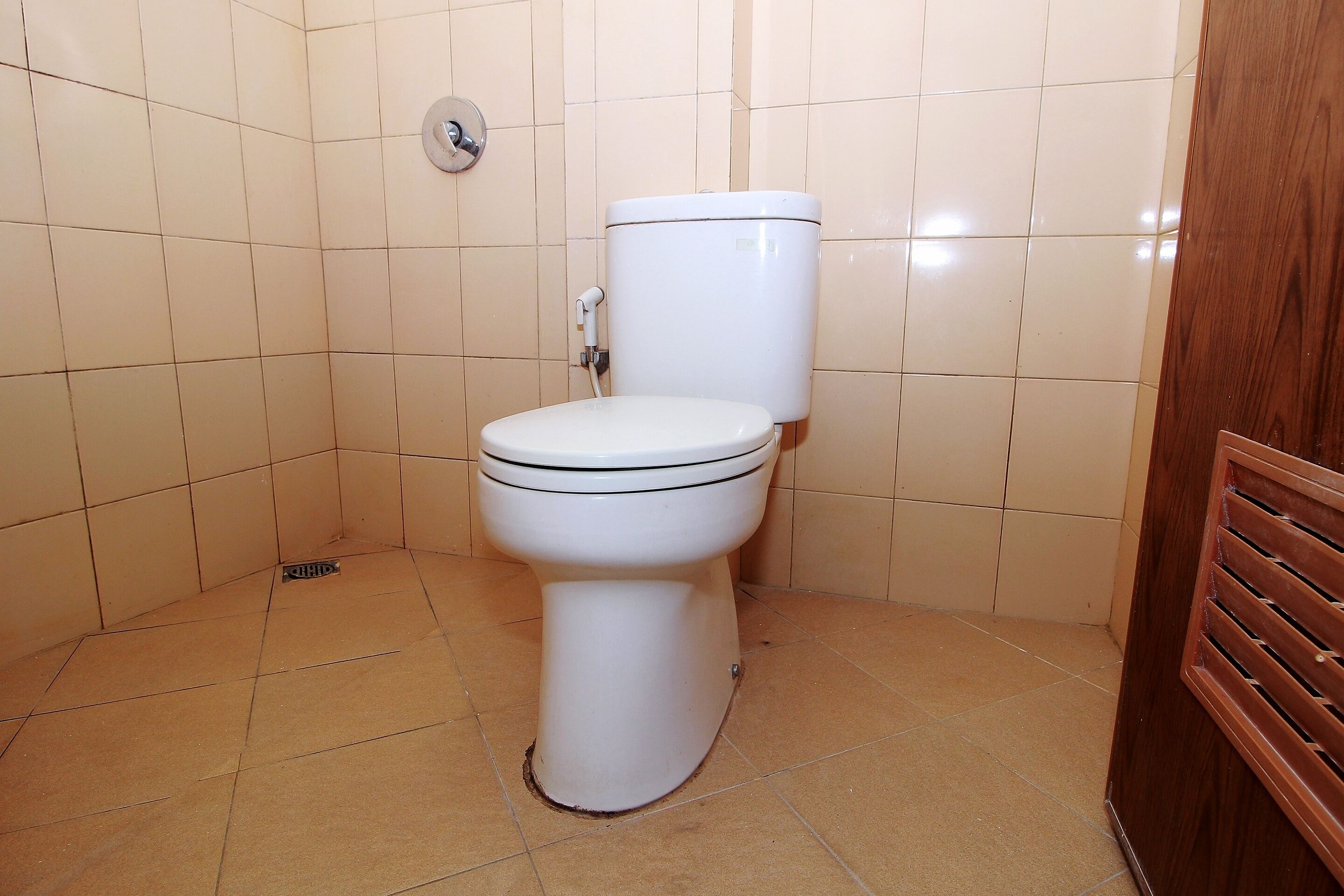 Een standaard toilet in een badkamer met betegelde wanden en vloer.