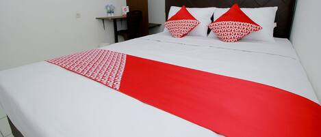 Ein Hotelzimmer mit Bett, Kissen, Nachttisch und Stuhl.