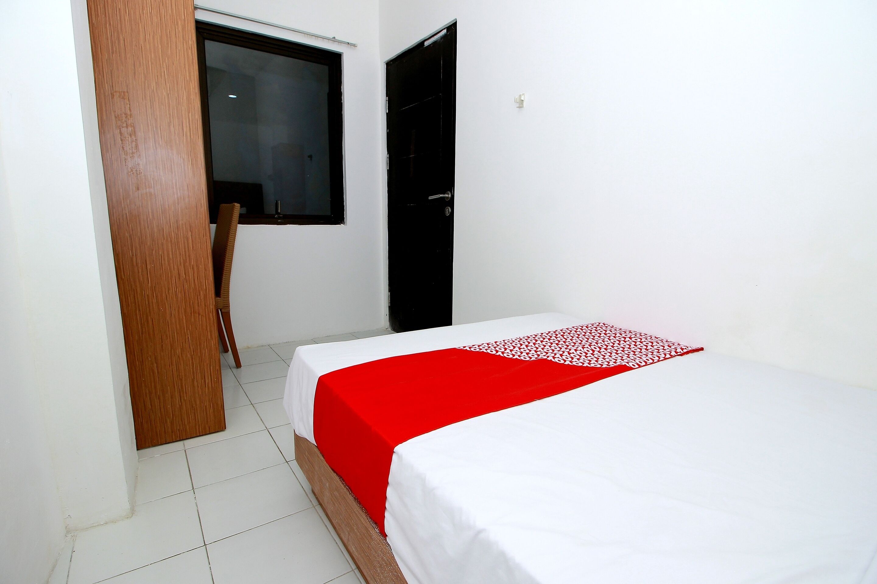 Ein Zimmer mit einem Bett, einer Holztür und einem Fenster.