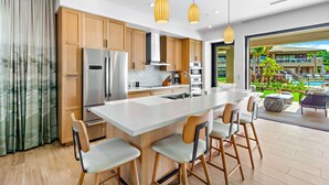 A modern kitchen with wooden cabinets, stainless steel appliances, and a central island with bar stools.