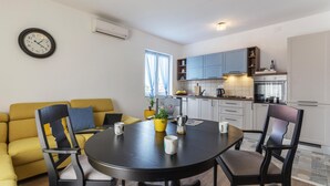 A compact living space with a dining area, a sofa, a kitchen, and a wall clock. - Nice apartment in Fazana with WiFi (Fazana)
