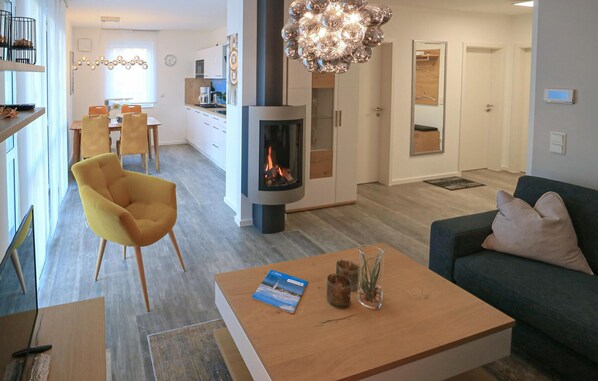 A modern living room with a sofa, a yellow chair, a coffee table with a book and candles, and a fireplace. - Awesome apartment in Rechlin with house sea view (Rechlin)