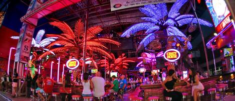 A bar area with neon palm tree decorations and stools.