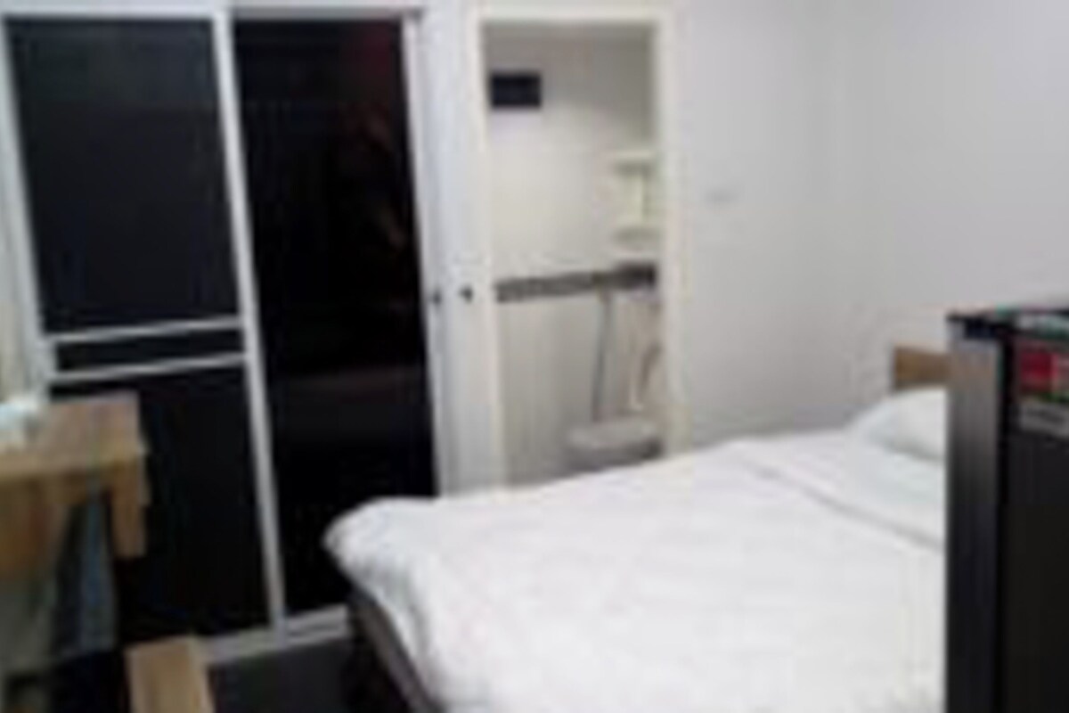 Un dormitorio con cama, armario y un pequeño escritorio.