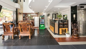 A modern hotel lobby with wooden furniture, a vending machine, and a statue.