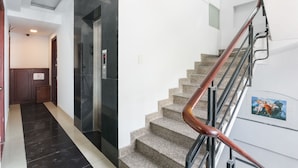 A modern interior with a staircase, a lift, and a hallway leading to a door.