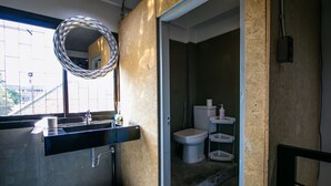 Un baño con lavamanos, espejo, inodoro y estantes.