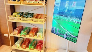 A shelf with packaged food items and a TV screen displaying a sports event. - Cloud Haku Cozy Inn (Taitung)