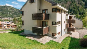 Ein mehrstöckiges Gebäude mit Balkonen vor einer Bergkulisse.