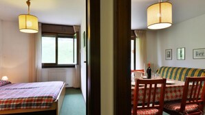 Ein Zimmer mit zwei Betten, einem Esstisch mit Stühlen und einem Sofa.
