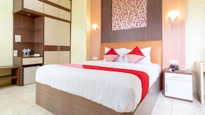 Una habitación de hotel con una cama grande, un armario, una mesita de noche y una mesilla.